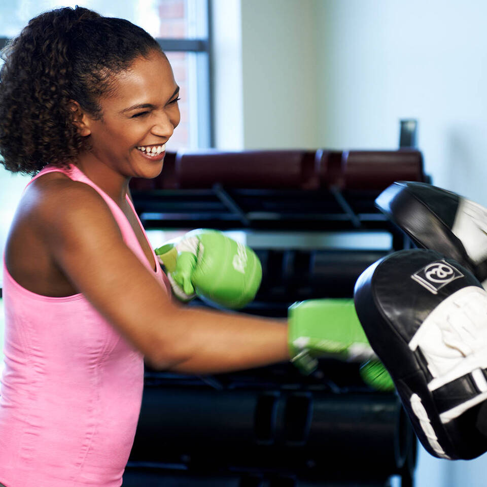A female health club member and female personal training using boxing gloves and pads